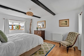 A bedroom with a bed, dresser, chair, and a radiator. - Romantic North Wales Meadow Cottage (Andover)