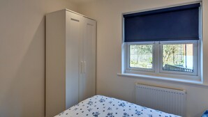A bedroom with a bed, a wardrobe, a window with a view, and a radiator. - Victorian Caernarfon House for 6 (Fowey)