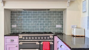 Una cocina con estufa a gas, horno y salpicadero de azulejos.
