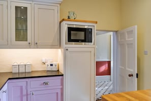 A kitchen with white cabinets, a microwave, a coffee maker, and a radio. - Pleasant Cottage in Banks of the River Fowey (Fowey)