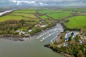 An aerial view of a coastal village with a marina, houses, and fields. - Pleasant Cottage in Banks of the River Fowey (Fowey)
