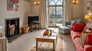 Una sala de estar acogedora con chimenea, televisor, sofá y una mesa de comedor preparada para el desayuno.