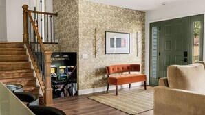 Ein Wohnzimmer mit einer Holztreppe, einer Bank, einem Teppich und einer Tür.