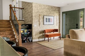 A living room with a wooden staircase, a bench, a rug, and a door. - Hot Tub, Game Room with Arcades, 3 King Beds, Fire Pit - Sleeps 11 (St. Peters)