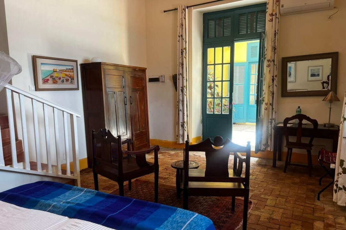 Una habitación con cama, escritorio, silla, armario y puerta que da al exterior.