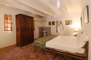 Una habitación con cama, armario, lavamanos y ventana con cortinas.