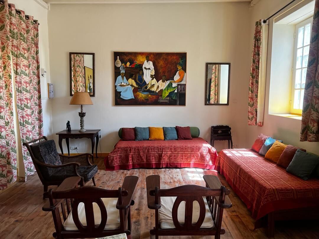 Una habitación con una cama, dos sillas, una mesa, un cuadro y una ventana.
