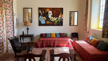 Una habitación con una cama, dos sillas, una mesa, un cuadro y una ventana.