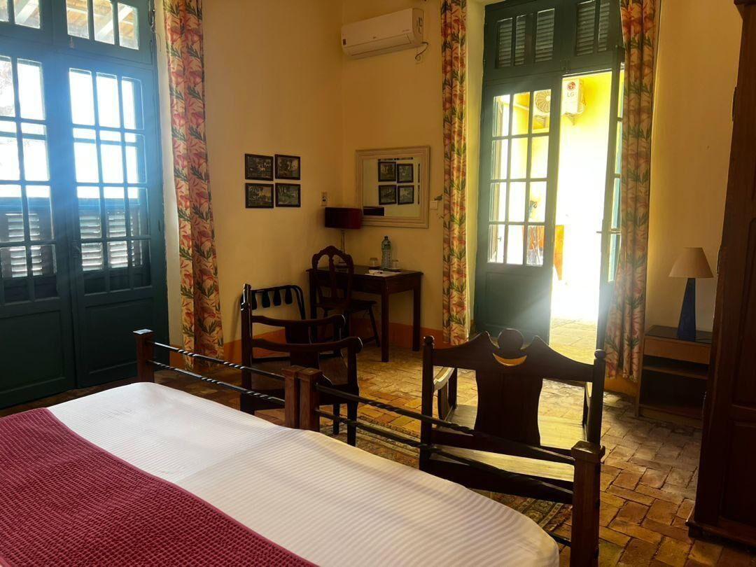 Una habitación con cama, escritorio, sillas y ventana con cortinas.
