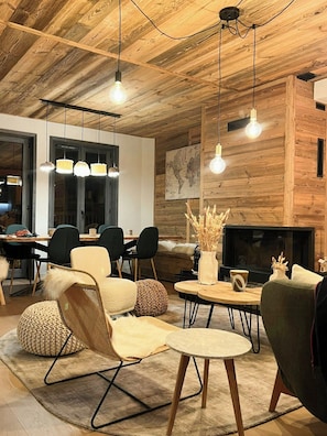 Ein modernes Interieur mit Holzbalkendecke, Kamin und Essbereich mit Stühlen und Tischen.
