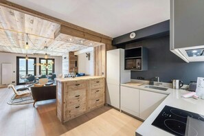 A modern kitchen with wooden cabinetry, a built-in microwave, and a central island with drawers. - Chalet-style apartment in Courchevel Village (Courchevel)
