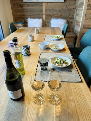 Ett matbord med en vinflaska, två glas och olika rätter.