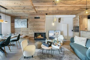 Ein modernes Wohnzimmer mit Kamin, Essbereich und Sitzgelegenheiten.