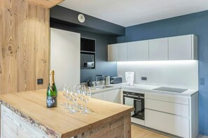 A modern kitchen with white cabinets, a wooden countertop, and a bottle of champagne. - Chalet-style apartment in Courchevel Village (Courchevel)