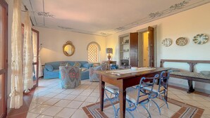 Ein gemütliches Wohnzimmer mit einer Couch, einem Esstisch mit Stühlen und dekorativen Tellern an der Wand.