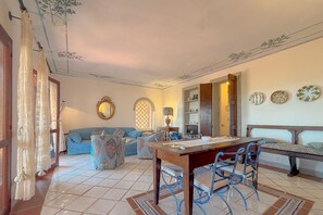 Ein gemütliches Wohnzimmer mit einer Couch, einem Esstisch mit Stühlen und dekorativen Tellern an der Wand.
