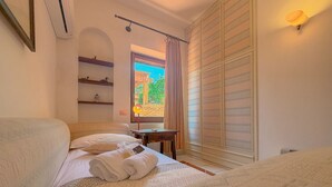 Ein Hotelzimmer mit Bett, Schreibtisch, einem Fenster mit Vorhängen und einem Kleiderschrank.