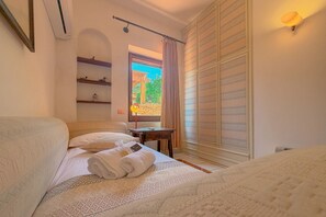 Ein Hotelzimmer mit Bett, Schreibtisch, einem Fenster mit Vorhängen und einem Kleiderschrank.