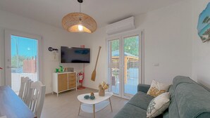 Ein modernes Wohnzimmer mit einem grauen Sofa, einem weißen Couchtisch und einem Fernseher an der Wand.