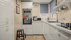 Uma cozinha com armários brancos, forno embutido, micro-ondas, pia e fogão.
