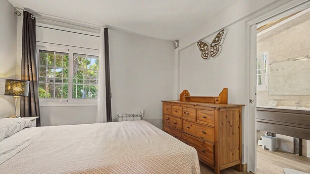 Quarto com cama, cômoda e janela com cortinas.