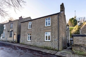 A two-story stone house with a brick facade, multiple windows, and a visible number '87' on the wall. - Cottage in Peak District National Park (Macclesfield)