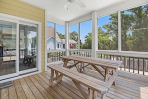 Eine überdachte Veranda mit Holzbanken und einer Glastür, die zu einer Terrasse führt.
