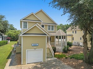 A two-story residential building with a garage, a covered porch, and a well-maintained lawn. - Calm C's: Dog Friendly | Hot Tub | Pool (Corolla)