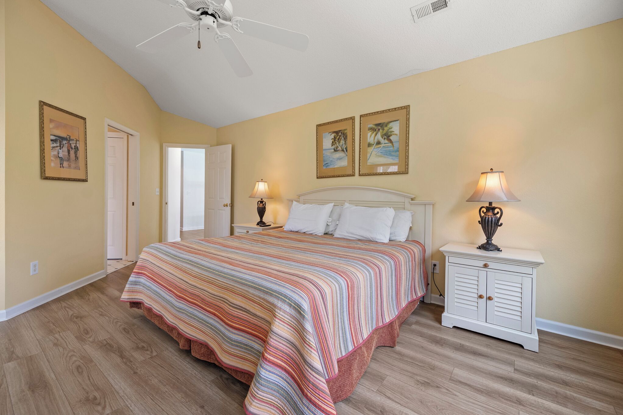 A bedroom with a bed, two bedside tables, a ceiling fan, and two wall-mounted lamps.