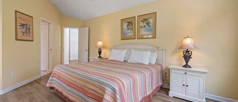 A bedroom with a bed, two bedside tables, a ceiling fan, and two wall-mounted lamps.