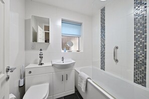 Un baño moderno con inodoro, lavamanos, espejo y ducha.