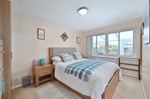 Ein Schlafzimmer mit Bett, Nachttisch, Lampe und einem Fenster mit Blick.