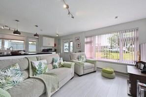 A spacious living room with a sofa set, a dining area, and a kitchen. - Historic Wiltshire Garden Cottage (Winchelsea)