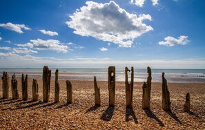 Ein Strand mit Holzpfählen und Kieselsteinen.