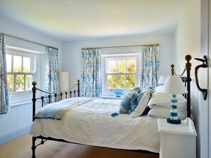 A bedroom with a bed, curtains, a nightstand, and a lamp. - Coastal Stay Near Coast Path (Kingsbridge)