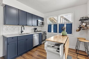 Una cocina moderna con armarios oscuros, un microondas, un lavamanos y una encimera de madera.