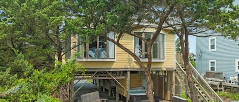 A two-story house with a deck, a hot tub, and a staircase leading to the upper level.