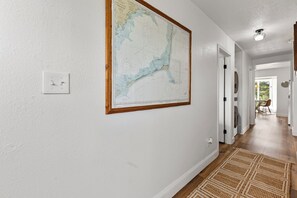 Un pasillo con un mapa en la pared, un interruptor de luz y una puerta que da a otra habitación.