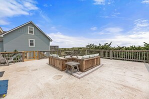 A covered outdoor patio with a wooden bench and table, a concrete floor, and a wooden fence. - Yellow Submarine: Oceanfront | Hot Tub, Deck (Salvo)