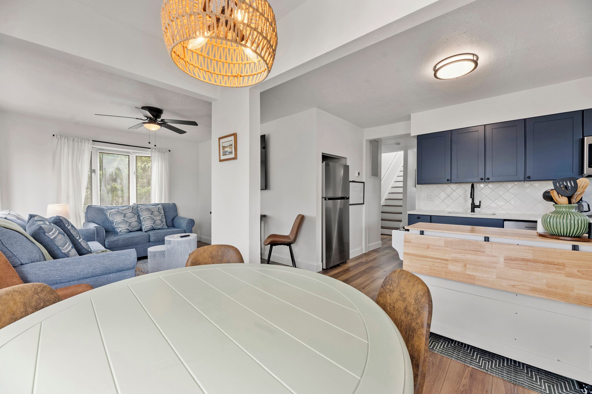 A modern living room with a sofa, a dining table, and a kitchen area with cabinets and appliances.
