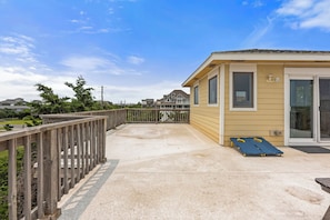 A covered outdoor area with a wooden deck, a small building with a sliding glass door, and a view of a residential neighborhood.