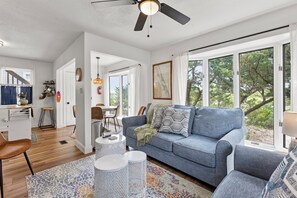 Un salon moderne avec un canapé gris, une table basse et un coin repas comprenant une table et des chaises.