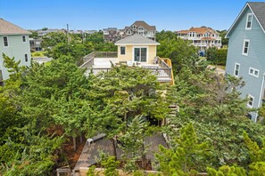 Un barrio residencial con varias casas, una casa central con porche y zonas verdes a su alrededor.
