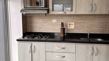 Una cocina moderna con estufa a gas, electrodomésticos de acero inoxidable y armarios de madera clara.