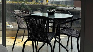 Un balcón con vistas a un puente atirantado, una mesa redonda con sillas y una planta en maceta.
