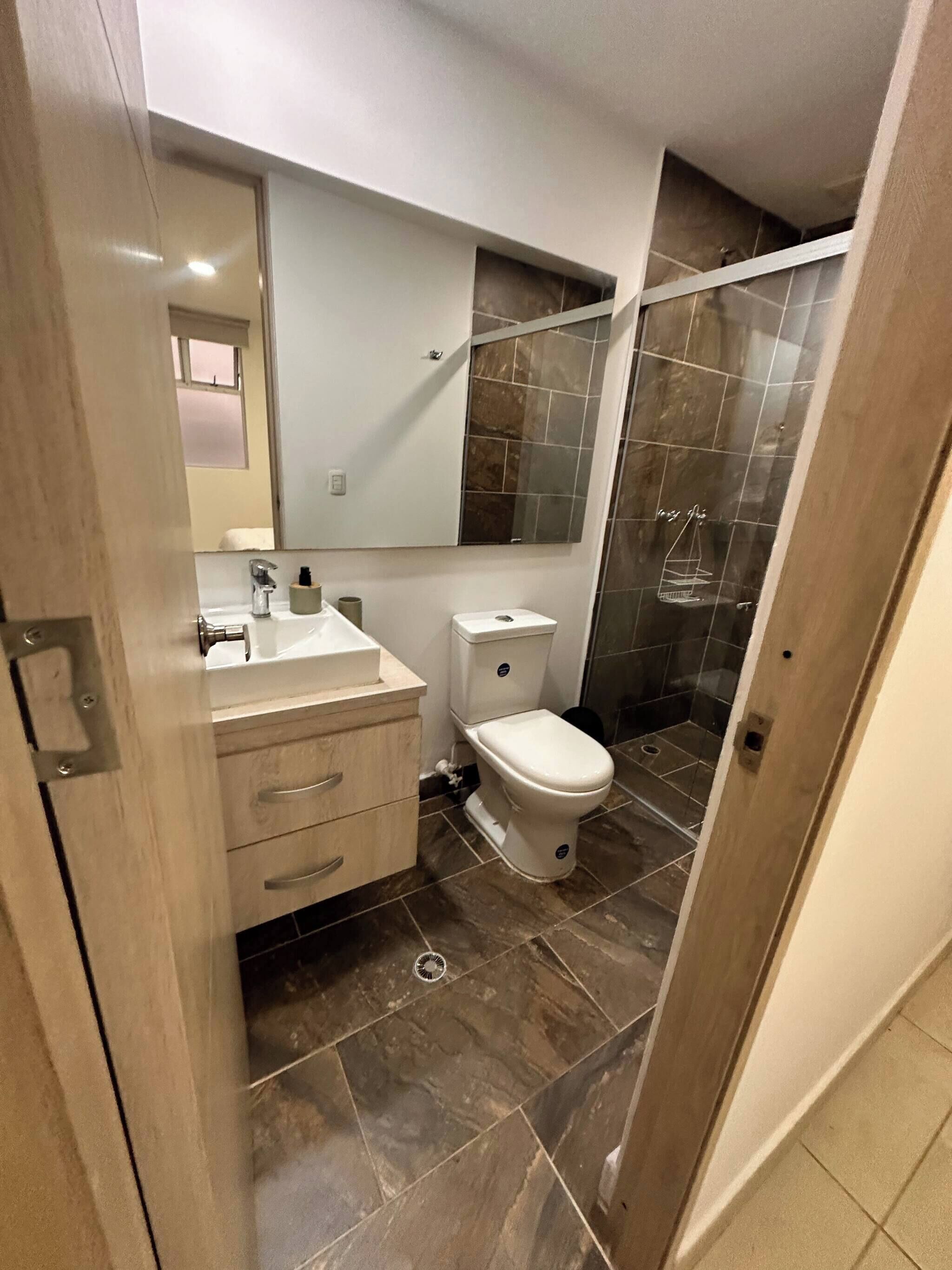 Un baño con inodoro, lavabo y espejo.