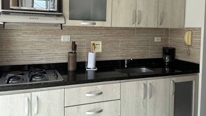Una cocina con estufa a gas, cafetera y microondas empotrado.
