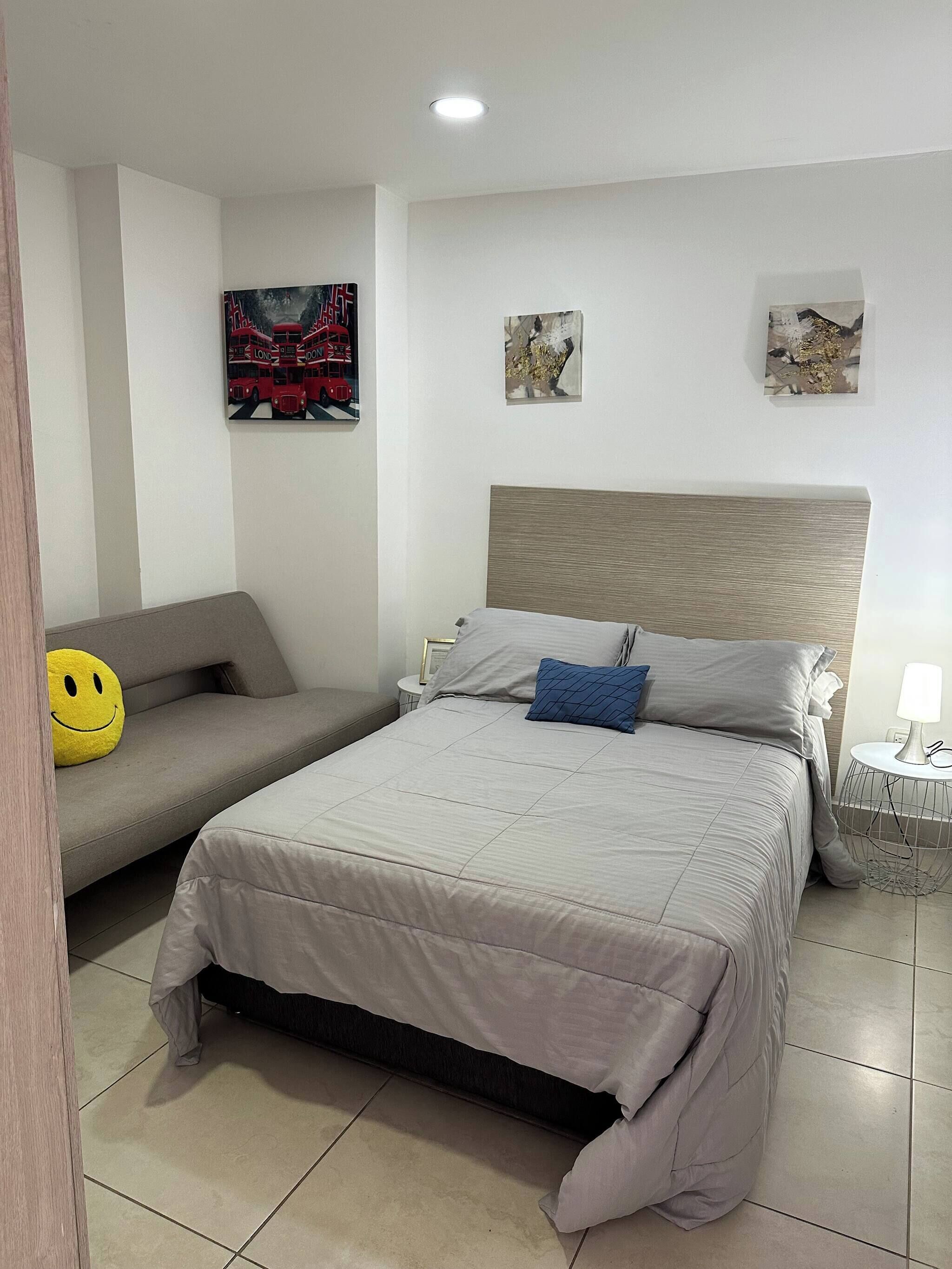 Un dormitorio con una cama, un sofá y una mesita.
