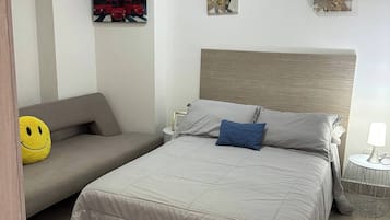 Un dormitorio con una cama, un sofá y una mesita.