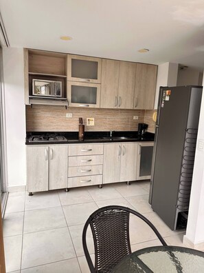 Una cocina con armarios de madera, un microondas, una estufa y un refrigerador.